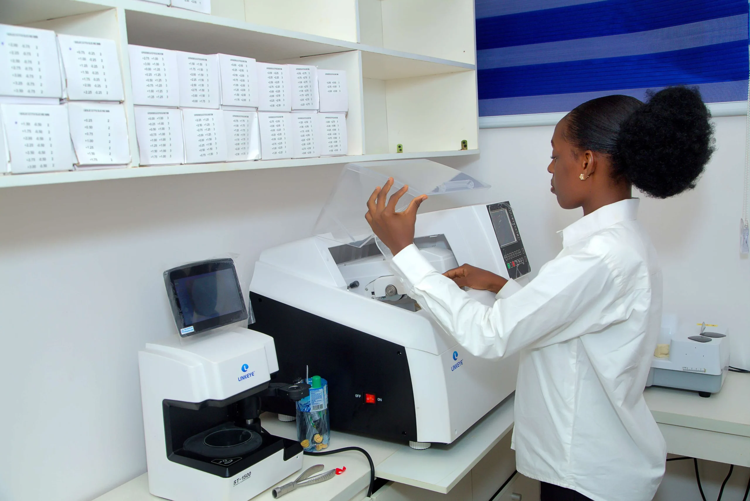 Optician using auto-edger at IrisCare Eye Clinic in Dopemu to glaze lenses